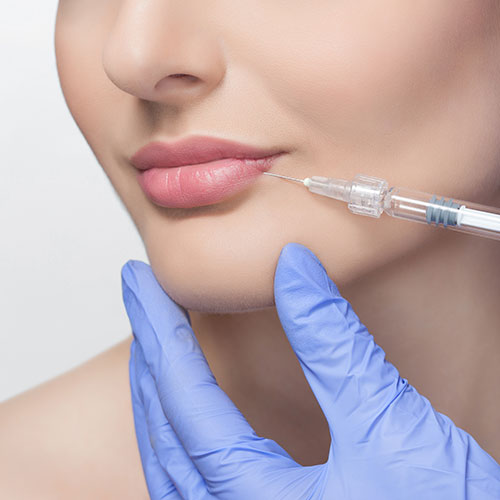 Female having lip filler injections by practitioner with purple gloves.